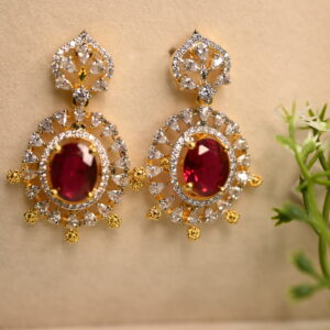 Image: A pair of elegant earrings are showcased on a beige surface, adorned with a delicate sprig of greenery in the corner. Earrings: Style: Drop earrings with a classic, ornate design. Color: The earrings are primarily gold-toned. CZ Earring