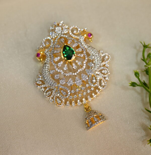 A teardrop-shaped pendant with a gold-plated frame, adorned with sparkling cubic zirconia stones and a central green gemstone.