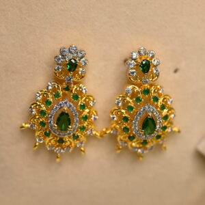 The image shows a pair of elegant earrings. They are made of gold and adorned with sparkling white and green CZ diamonds. The design is intricate, featuring a floral motif with delicate filigree work. The earrings have a drop style, with the diamonds cascading downwards. The overall effect is one of luxury and sophistication.