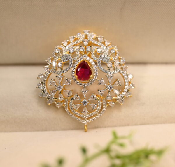 The image shows a close-up of a jewelry pendant. The pendant appears to be made of gold or a gold-toned metal.