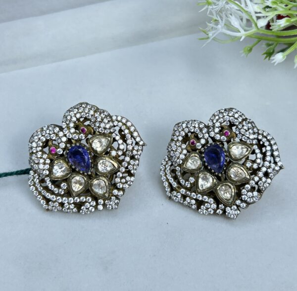 The image shows a pair of stunning earrings. They are made of silver and adorned with a mix of white and blue stones. The design is intricate and detailed, with a floral motif. The earrings look like they would be perfect for a special occasion.