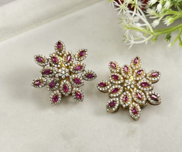 The image showcases a pair of elegant earrings featuring a radiant floral design. The earrings appear to be made with high-quality moissanite stones, set in a lustrous metal, likely gold or silver.