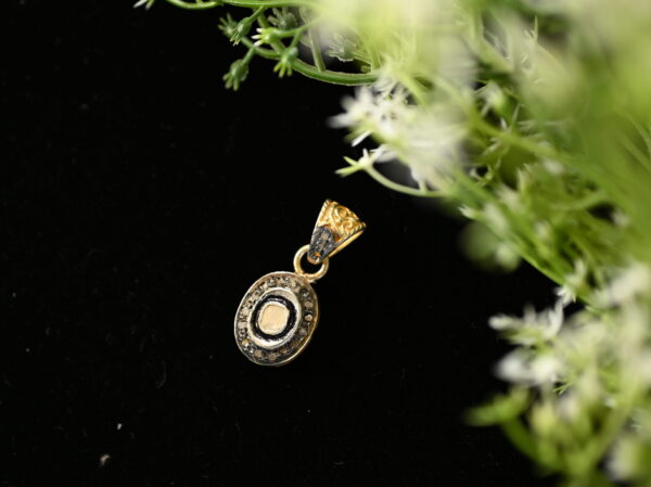 The image shows a beautiful oval-shaped diamond pendant. The central diamond is surrounded by a delicate halo of smaller diamonds, creating a sparkling and eye-catching design. The pendant appears to be made of gold or silver, and it hangs from a simple bail. The overall impression is one of elegance and sophistication.