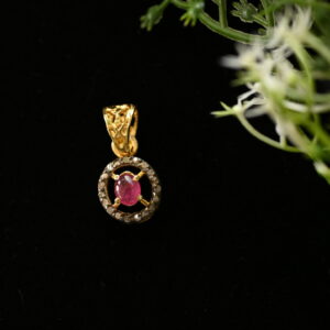 The image shows a close-up of a delicate pendant necklace. The pendant is made of 925 silver and features a central oval-shaped ruby gemstone. The ruby is surrounded by a circular halo of smaller diamonds, creating a dazzling contrast. The pendant hangs from a thin silver chain, and the background is a dark color, possibly black velvet, which makes the pendant stand out even more.