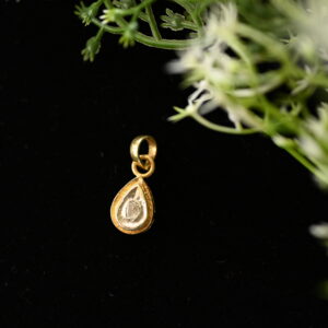 The pendant appears to be handcrafted, given the slightly uneven edges and rustic charm. The black background and delicate greenery in the image enhance the pendant's beauty and create a sense of luxury.