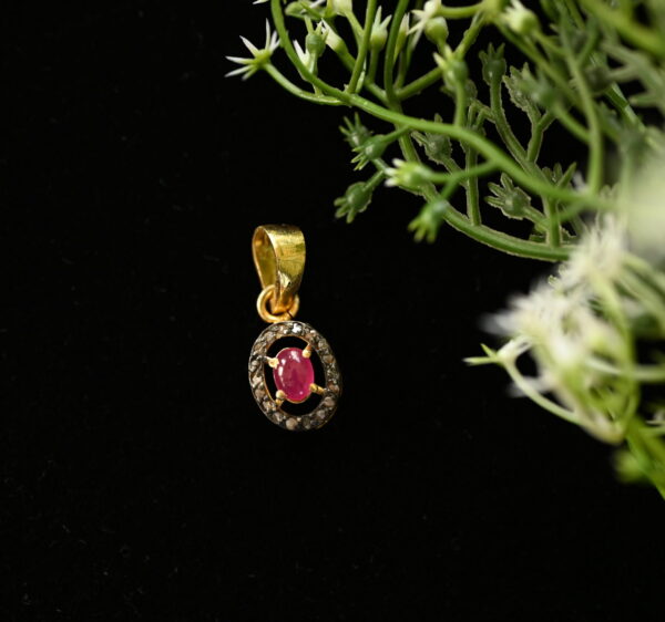 The image shows a beautiful pendant necklace. It appears to be made of 925 sterling silver. The pendant features a vibrant red ruby as the centerpiece, encircled by a halo of sparkling diamonds. The overall design is delicate and elegant. The pendant is showcased against a dark background, creating a striking contrast that highlights its brilliance. There are also some leafy green branches with tiny white flowers in the background, adding a touch of nature to the scene.