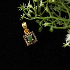 The image evokes a sense of elegance and understated luxury. The combination of the green gemstone and the sparkling diamonds creates a visually appealing contrast. The dark background further highlights the pendant's intricate details.
