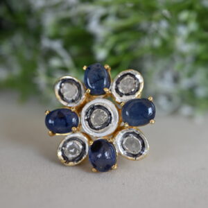 The image shows a beautiful ring made of 925 sterling silver. The ring features a cluster of sparkling diamonds in the center, surrounded by a collection of blue sapphires. The overall design is elegant and timeless, with a touch of classic charm. The ring is likely to be a statement piece that can be worn on various occasions.