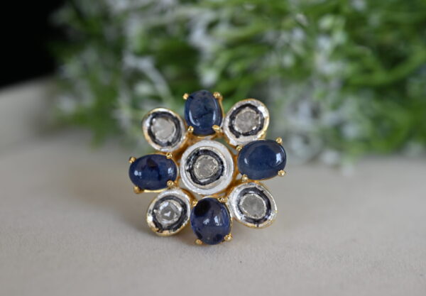 The image shows a beautiful ring made of 925 sterling silver. The ring features a cluster of sparkling diamonds in the center, surrounded by a collection of blue sapphires. The overall design is elegant and timeless, with a touch of classic charm. The ring is likely to be a statement piece that can be worn on various occasions.
