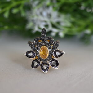 The image showcases a stunning ring with a vintage-inspired design. Central Feature: A prominent yellow gemstone, likely a yellow sapphire or topaz, takes center stage. It is surrounded by a cluster of smaller, colorless diamonds. Design Elements: The ring appears to be crafted in gold, possibly yellow gold.