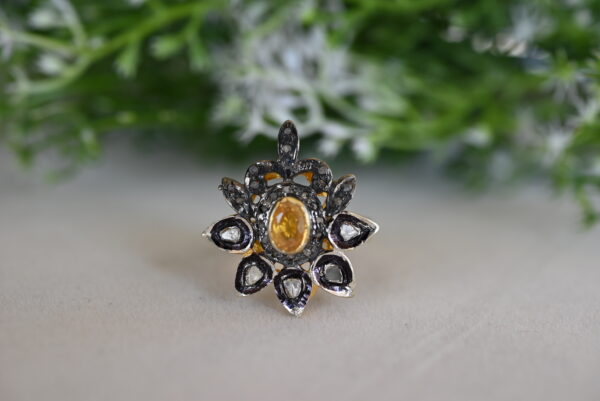 The image showcases a stunning ring with a vintage-inspired design. Central Feature: A prominent yellow gemstone, likely a yellow sapphire or topaz, takes center stage. It is surrounded by a cluster of smaller, colorless diamonds. Design Elements: The ring appears to be crafted in gold, possibly yellow gold.