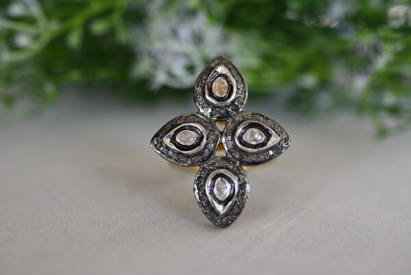 The image shows a pair of stunning diamond earrings. The earrings feature a traditional Indian Polki design, where uncut diamonds are set in gold. The Polki diamonds are large and lustrous, creating a luxurious and elegant look. The earrings have a unique floral motif, with intricate detailing and delicate filigree work.