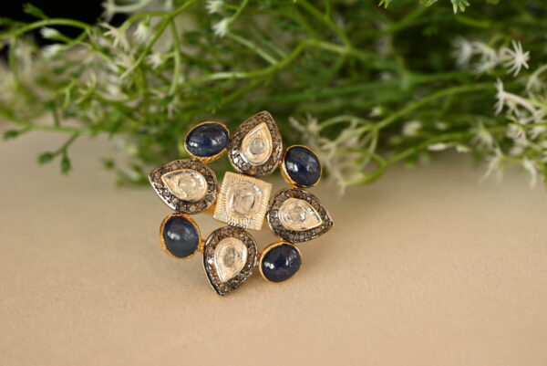 The image shows a beautiful ring with a floral design. It is adorned with a combination of sparkling diamonds and vibrant blue sapphires, creating a stunning contrast. The ring appears to be crafted in gold, adding to its luxurious appeal. The intricate details and fine craftsmanship are evident in the way the stones are set and the overall design of the ring.