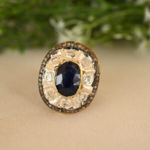 The image you sent shows a beautiful ring with a large, oval-shaped blue sapphire as the center stone. The sapphire is a deep, rich blue color and appears to be of high quality. It's surrounded by a halo of smaller diamonds, which add sparkle and enhance the sapphire's brilliance. The ring's band looks to be made of gold, possibly yellow gold, and it has intricate details like small diamonds or milgrain.