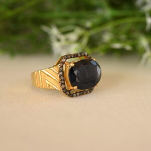 The image you sent shows a vintage-style ring with a large, oval-shaped sapphire as the centerpiece. The sapphire has a deep blue color and is surrounded by a halo of smaller diamonds. The ring band appears to be made of gold and features a wide, textured design. The ring looks quite substantial and luxurious.