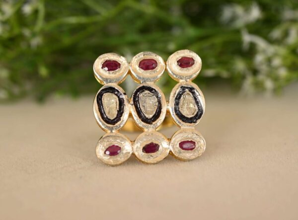 The image showcases a stunning ring, likely made of 925 silver, adorned with a captivating array of diamonds and rubies. The ring features a rectangular centerpiece with three rows of meticulously set stones. The top and bottom rows display a cluster of five round-cut rubies, their deep red hue adding a touch of dramatic elegance. The middle row features five round-cut diamonds, their brilliance and sparkle adding a touch of timeless sophistication. The ring rests on a textured surface, possibly a fabric or a stone, with a blurred green background suggesting foliage.