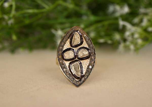 This image features a stunning pear-shaped cocktail ring crafted in 925 sterling silver. The ring is adorned with a captivating array of natural rose-cut polki diamonds, meticulously set in a pave setting that accentuates their brilliance. The center stone, a pear-shaped rose-cut diamond, takes center stage, commanding attention with its unique shape and captivating sparkle.