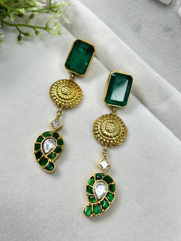 The image shows a pair of elegant earrings. Shape: The main part of the earring seems to be a rectangular or square shape, possibly made of metal. Material: The earrings are likely made of metal, possibly gold-plated or silver. Color: The earrings appear to have a warm, golden color, which would complement a variety of skin tones.