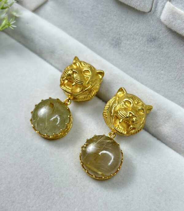 The image shows a pair of gold-toned earrings with a tiger head design.