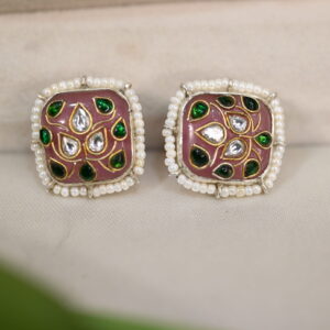 The image shows a pair of elegant fusion earrings. The earrings have a square base adorned with a floral motif created using the intricate Meenakari technique. The Meenakari work features vibrant green and pink enamels, creating a striking contrast against the silver base. Delicate white pearls encircle the motif, adding a touch of elegance.