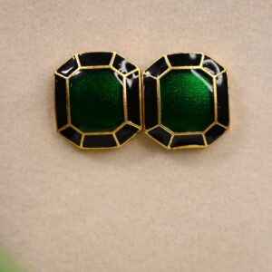 The image shows a pair of statement earrings. Each earring features a large, square-shaped gemstone in a vibrant shade of green. The gemstone is faceted and set in a sleek, gold-toned frame with a contrasting black border. The earrings appear to be made with high-quality materials and craftsmanship.