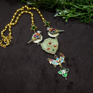 The image showcases a fusion necklace with a captivating blend of traditional and contemporary aesthetics. The centerpiece is a beautifully carved jade pendant, adorned with intricate enamel work in vibrant hues of red, green, and blue. This is further embellished with sparkling white diamonds and other colorful gemstones, adding a touch of luxury and elegance.