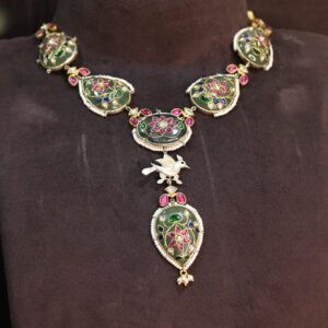 The necklace appears to be crafted with high-quality materials and meticulous attention to detail. The pendant's design suggests a floral or nature-inspired theme. The dark background and the soft lighting create a dramatic and luxurious backdrop for the necklace.