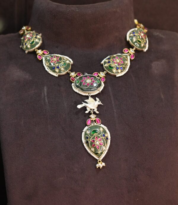 The necklace appears to be crafted with high-quality materials and meticulous attention to detail. The pendant's design suggests a floral or nature-inspired theme. The dark background and the soft lighting create a dramatic and luxurious backdrop for the necklace.