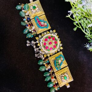 The image shows a beautiful fusion necklace. It features a central square motif adorned with intricate Meenakari work in vibrant colors like pink, green, and blue. The Meenakari work is complemented by sparkling white stones, adding a touch of elegance. Premium