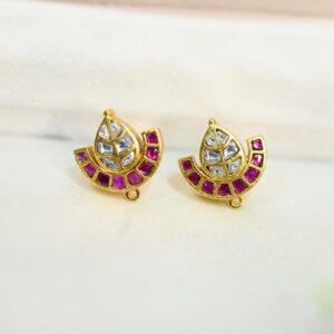 The image appears to show a pair of earrings. They are made of gold and feature a design with white and red stones. The white stones are likely Kundan, a traditional Indian gemstone. The red stones could be rubies or other red gemstones. The earrings have a leaf-shaped motif with a crescent-shaped element at the base. The overall style is classic and elegant, typical Kundan of Indian Kundan jewelry.