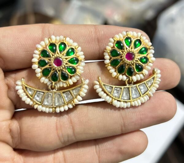 The image shows the earrings being held in a hand, which gives a sense of scale and allows viewers to appreciate the size and details of the jewelry. The background of the image is blurred, which helps to focus attention on the earrings.