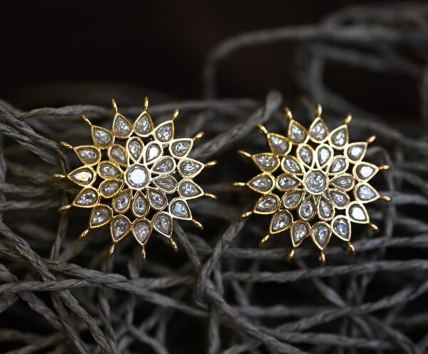 The image shows a beautiful ring with a floral design. It appears to be made of gold and is adorned with white gemstones, possibly diamonds or polki. The ring has a delicate and intricate design, with the gemstones arranged in a way that resembles a blooming flower. The overall effect is one of elegance and sophistication. "Radiant Kundan Earrings"