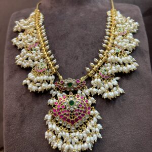 The image showcases a beautiful necklace adorned with traditional Indian jewelry elements. It appears to be a Guttapusalu necklace, characterized by its distinctive design with multiple chains and pendants.