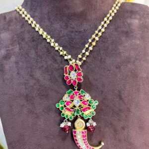 The image showcases a stunning necklace adorned with intricate Kundan work. The necklace features a captivating pendant design, adorned with a mesmerizing array of colorful gemstones.