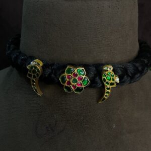 The image shows a close-up of a traditional Indian necklace. The necklace is made with a black velvet base, and it features three main elements: