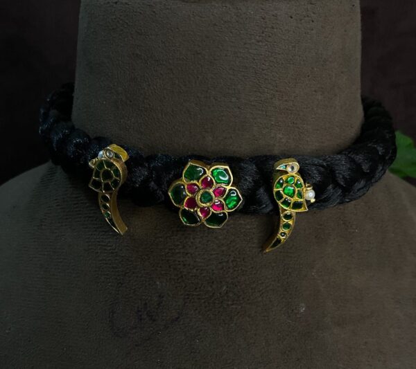The image shows a close-up of a traditional Indian necklace. The necklace is made with a black velvet base, and it features three main elements: