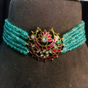 "A close-up of a gold Kundan choker necklace with a large crescent moon pendant set with colorful gemstones." Celestial Moon Kundan Pendant