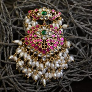 The image showcases a pair of elaborate earrings, likely inspired by the designs of renowned Indian fashion designer Sabyasachi Mukherjee.