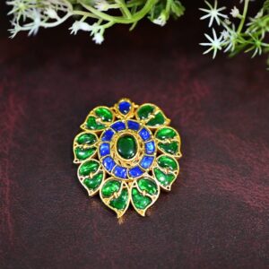The image shows a close-up of a beautiful Kundan pendant. The presence of delicate green foliage adds a touch of natural beauty to the image.