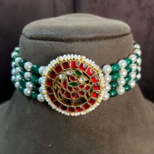 The image showcases a beautiful choker necklace | Pendant adorned with vibrant colors and intricate details. It appears to be a traditional Indian design, possibly inspired by Mughal or Rajasthani styles. "Red & Green Kundan Floral Pendant"