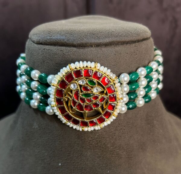 The image showcases a beautiful choker necklace | Pendant adorned with vibrant colors and intricate details. It appears to be a traditional Indian design, possibly inspired by Mughal or Rajasthani styles. "Red & Green Kundan Floral Pendant"
