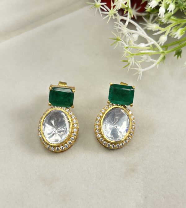 The image shows a pair of elegant earrings featuring a combination of moissanite and emerald gemstones.