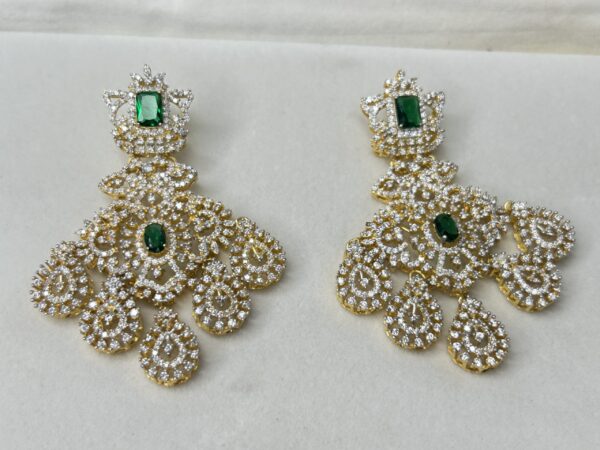 The image shows a pair of elegant earrings with a unique design. They appear to be made of silver and feature a central drop with a delicate filigree pattern. The earrings have a vintage or antique aesthetic, possibly inspired by Victorian or Edwardian jewelry.