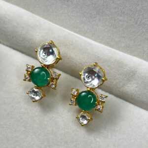 Center Stone: Each earring has a large, oval-shaped green gemstone, likely an emerald. Setting: The emerald is set in a gold-colored metal with a halo of smaller, round white gemstones. This halo adds a touch of sparkle and dimension. Design: The earrings have a delicate, feminine design with intricate details. They might have a dangling element or a small motif below the main stone.