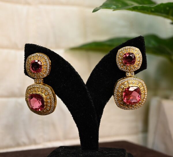 The image shows a pair of elegant dangle earrings. The earrings are made of silver and feature two large, square-cut pink gemstones. These gemstones are likely rubellites, a type of tourmaline known for its vibrant pink color.