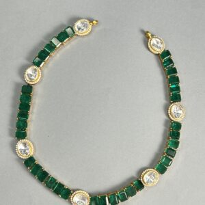 The image you sent shows a necklace made with a combination of emerald-cut and round-cut moissanites. The necklace appears to be a choker style, sitting close to the neck. The moissanites are set in a gold-plated setting, creating a luxurious and warm look. The overall design is minimalist and elegant, with clean lines and simple geometric shapes.