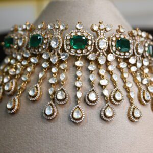 The image showcases a beautiful necklace crafted with moissanites. The necklace features a central cluster of emerald-cut moissanites, surrounded by a halo of smaller, pear-shaped moissanites. Delicate chains of teardrop-shaped moissanites cascade downwards from the central cluster, creating a mesmerizing waterfall effect. The overall design is reminiscent of traditional Indian jewelry with a contemporary touch. 925 Silver