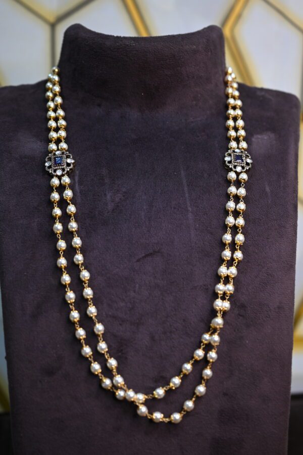 The image shows a necklace with a double strand of pearls and two prominent embellishments. The pearls are white and appear to be evenly sized and spaced along the strands. 925 Silver Jewellery
