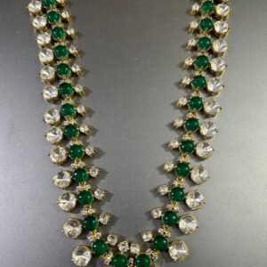 The image shows a necklace. It appears to be made of gold and features a repeating pattern of round, faceted gemstones. The gemstones alternate between a clear color and a deep green. The necklace has a long, flowing design with multiple strands. Unique Moissanite Necklace