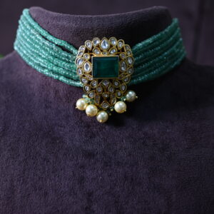 The image you sent shows a beautiful necklace with a central emerald gemstone and a halo of sparkling moissanites. The necklace also features a delicate floral design and a row of pearls, creating a truly unique and captivating look.